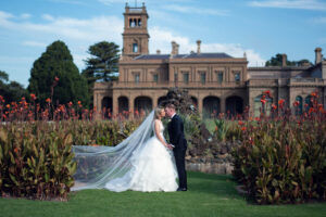 A newlywed couple kissing in front of an ancient castle