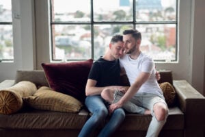 Two handsome Brisbane gay couple cuddling on their leather sofa in their loft